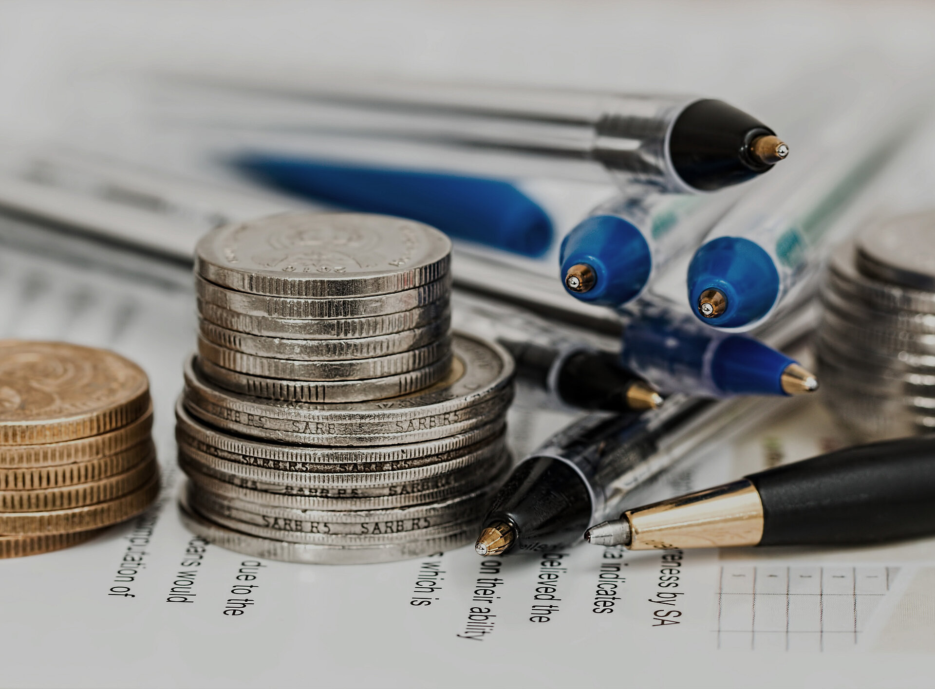 Nahaufnahme von Münzen und Kugelschreibern
